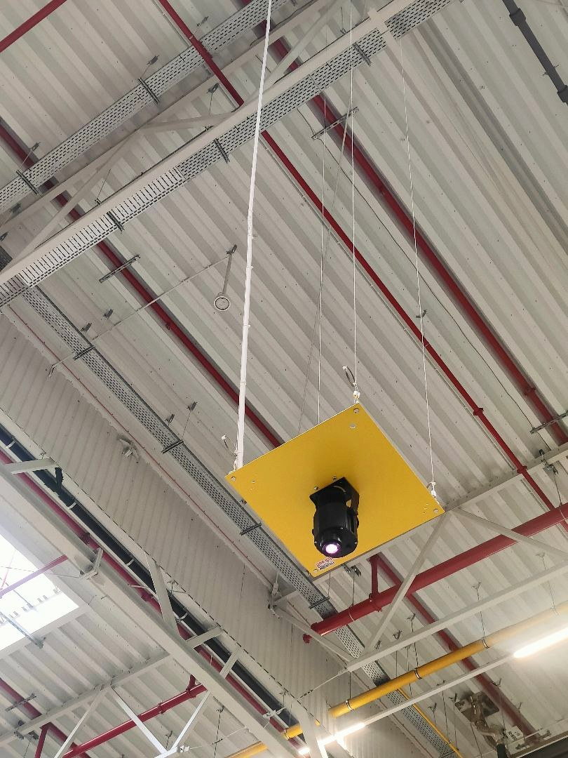 A projector on a suspended mounting plate under the roof of a hall