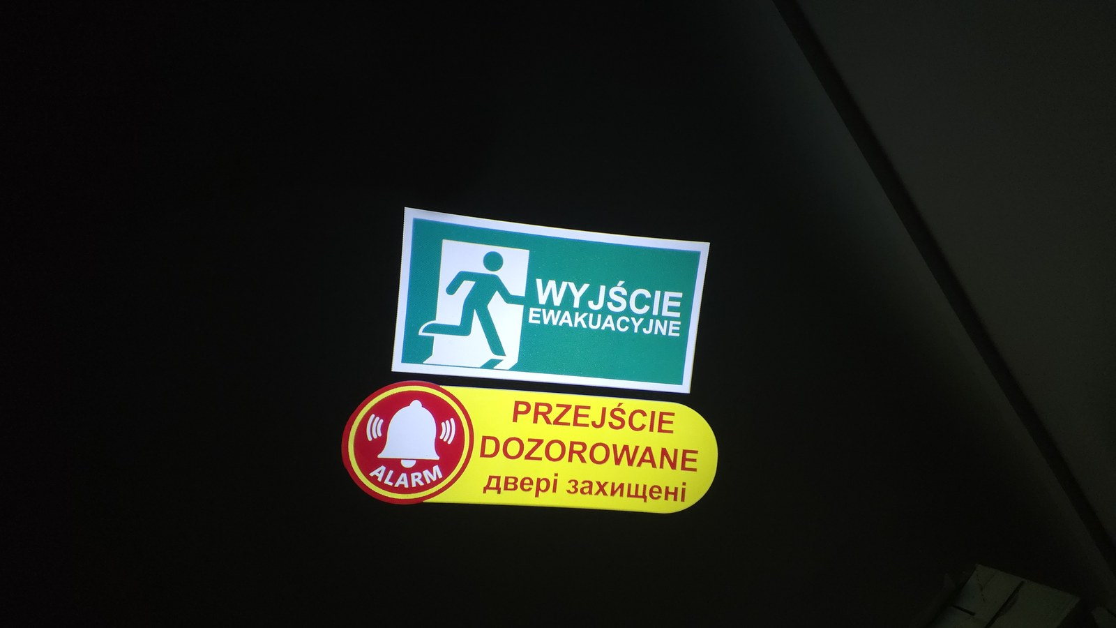 A message shown in Polish and Ukrainian in front of a monitored exit door